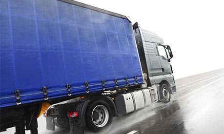 A blue lorry on a wet road