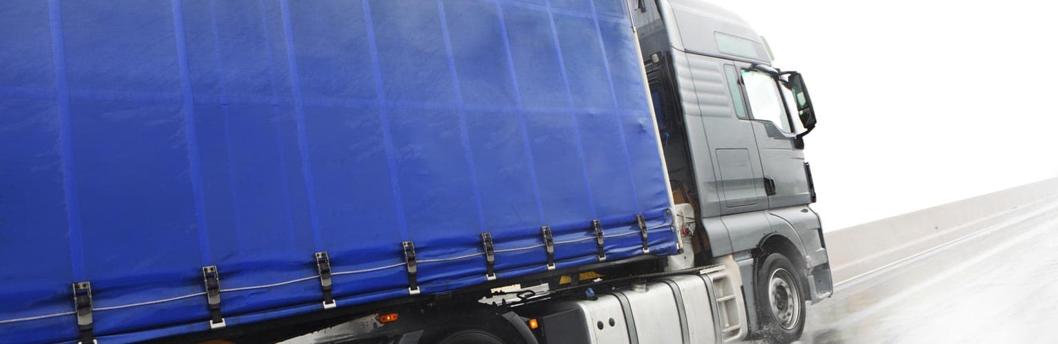 A blue lorry on a wet road