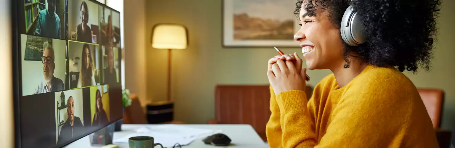 A woman in a yellow jumper smiling whilst working from her home office