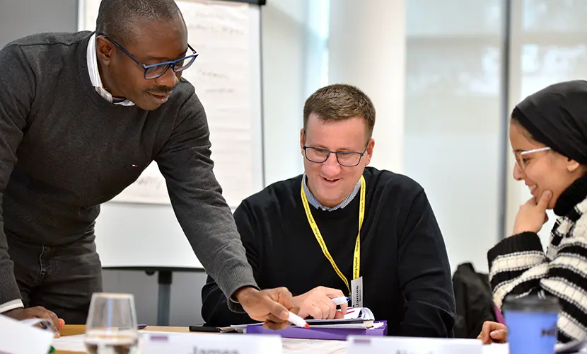 Three professionals sitting around a table discussing a project that they are working on together.