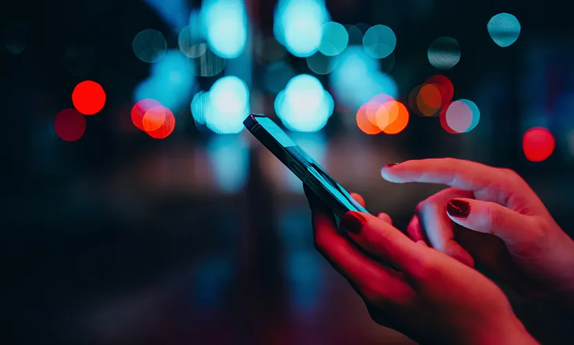 Someone holding a smartphone with city lights in the background