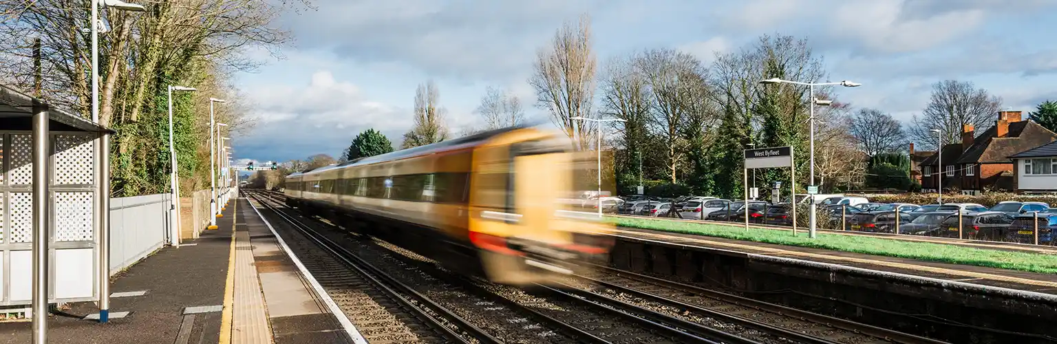 A train speeding through an empty station in Surrey.