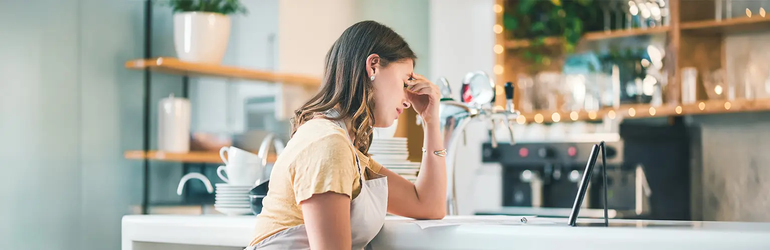 A young woman experiencing stress while working in a cafe.