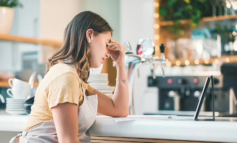 A young woman experiencing stress while working in a cafe.