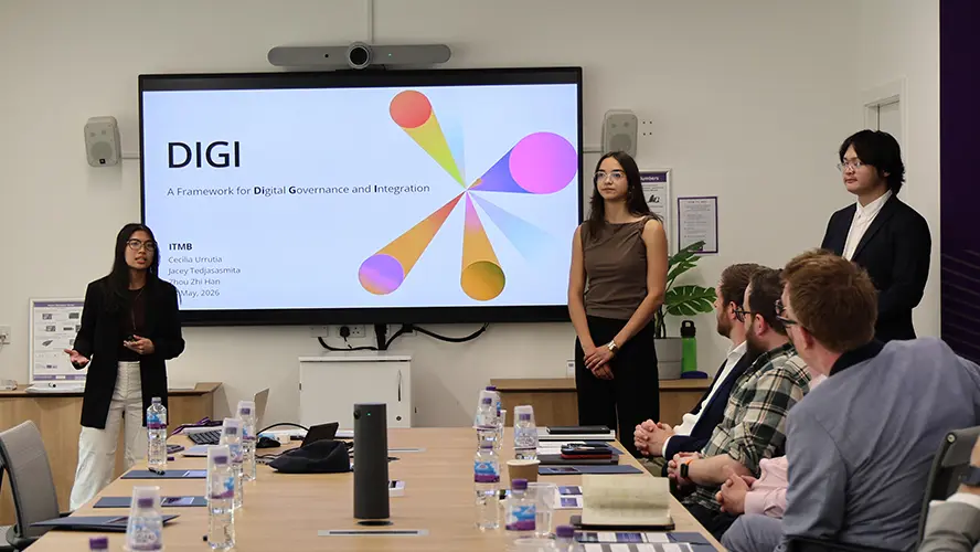 Three ITMB students presenting to two judges.