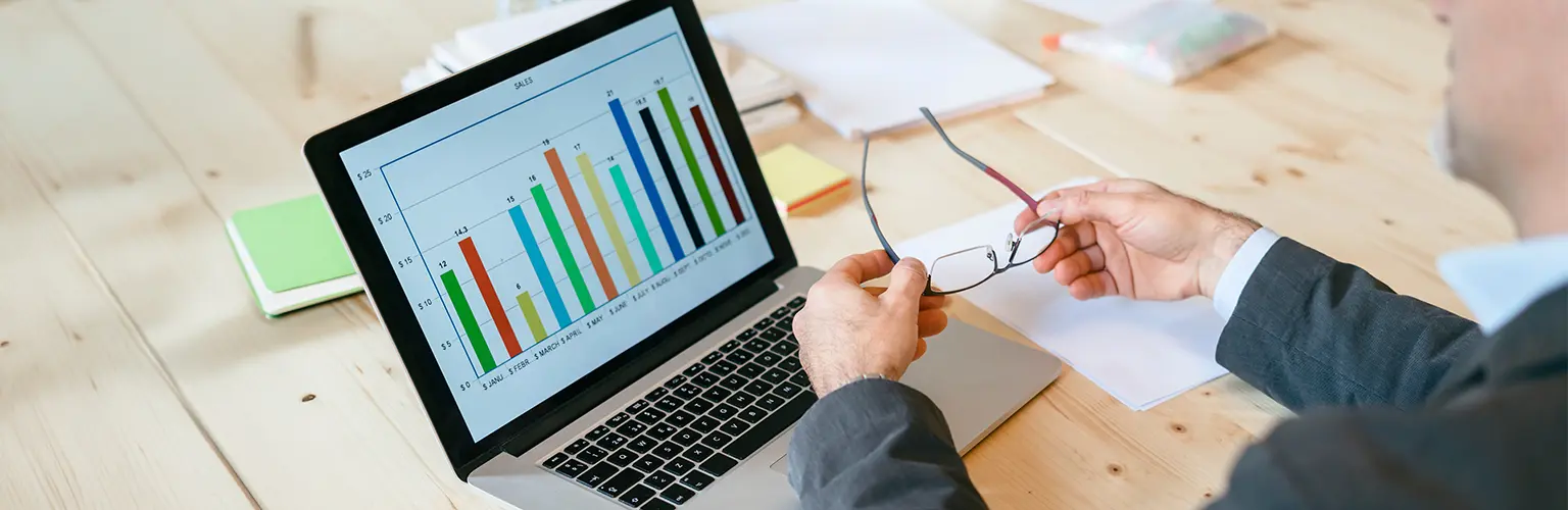 Business person looking at a bar chart on a laptop.