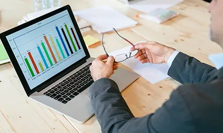 Business person looking at a bar chart on a laptop.