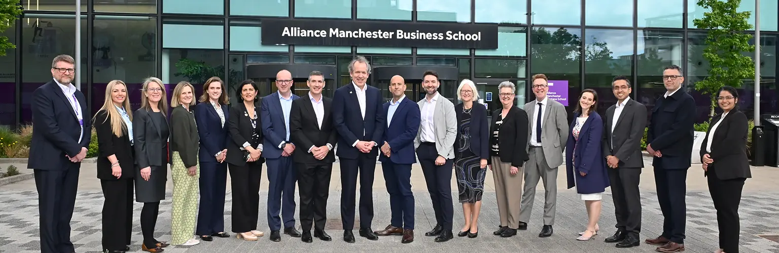 A large group of representatives from the University of Manchester executive, Alliance MBS, Unit M, and BNY standing in front of Alliance MBS building.