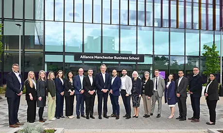 A large group of representatives from the University of Manchester executive, Alliance MBS, Unit M, and BNY standing in front of Alliance MBS building.