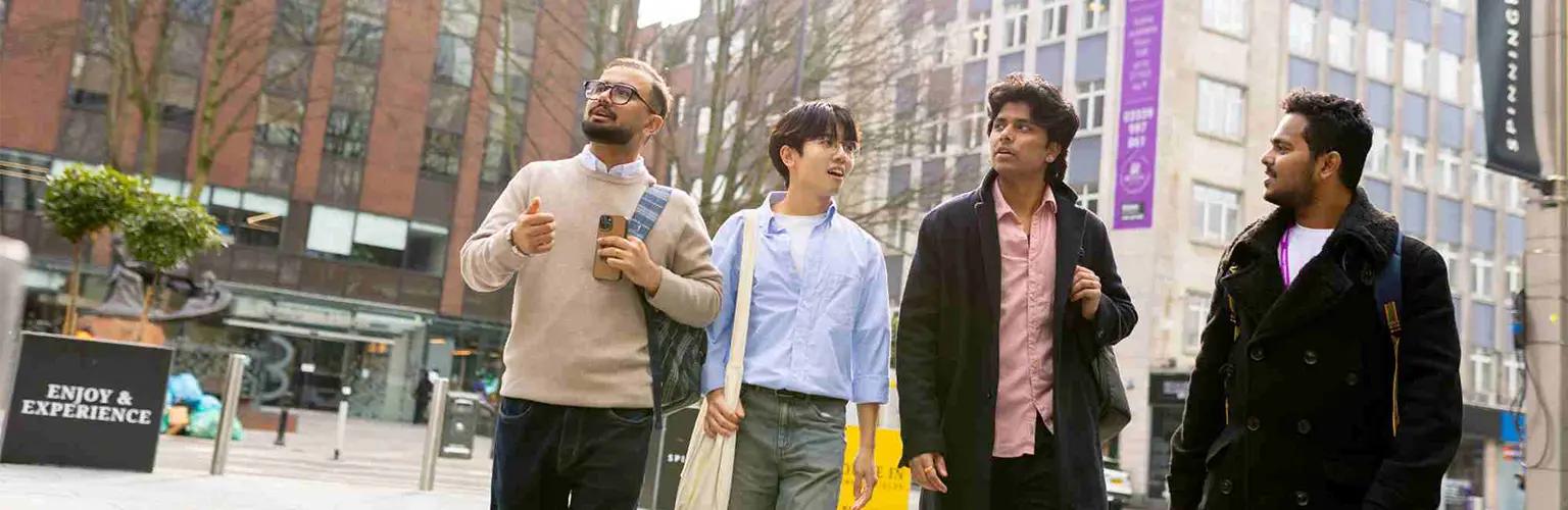 Four students walking through Manchester city centre.