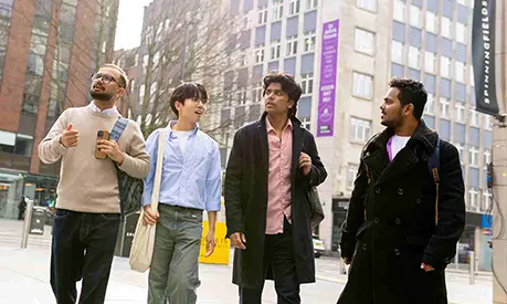Four students walking through Manchester city centre.
