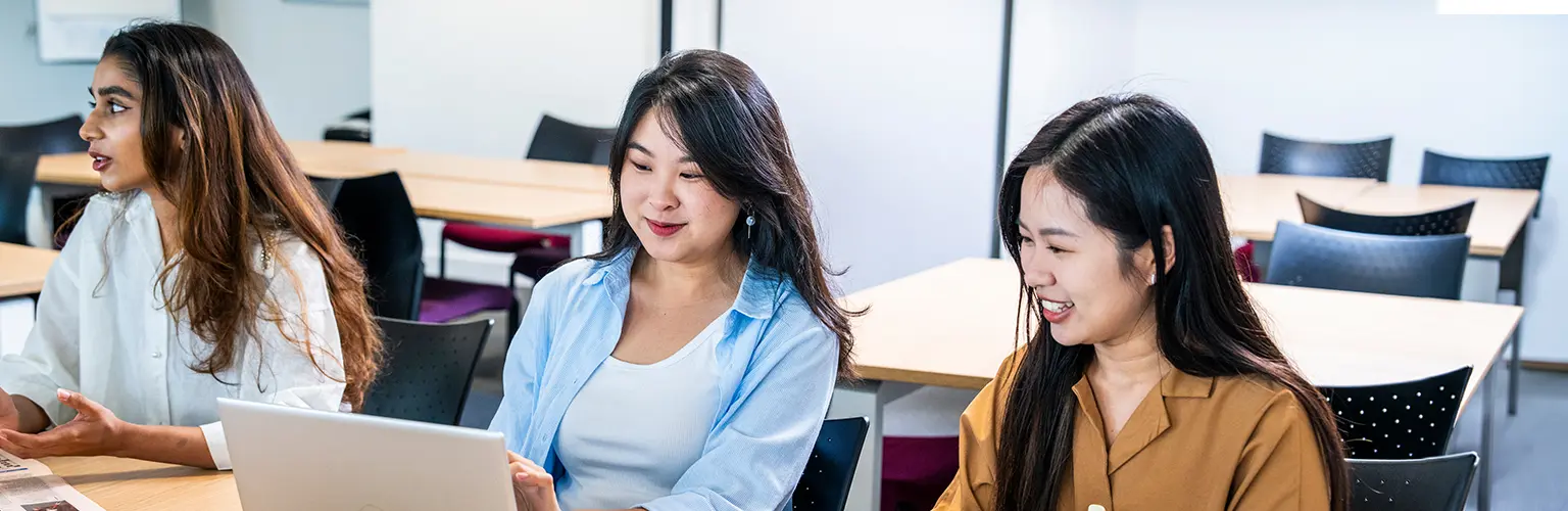 Three students working in a classroom.
