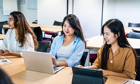 Three students working in a classroom.