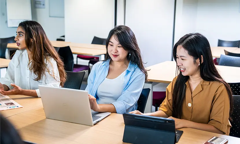 Three students working in a classroom.