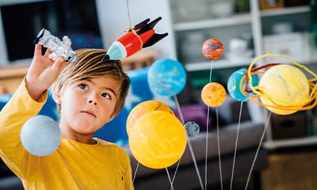 A child playing with a toy rocket and the toy solar system