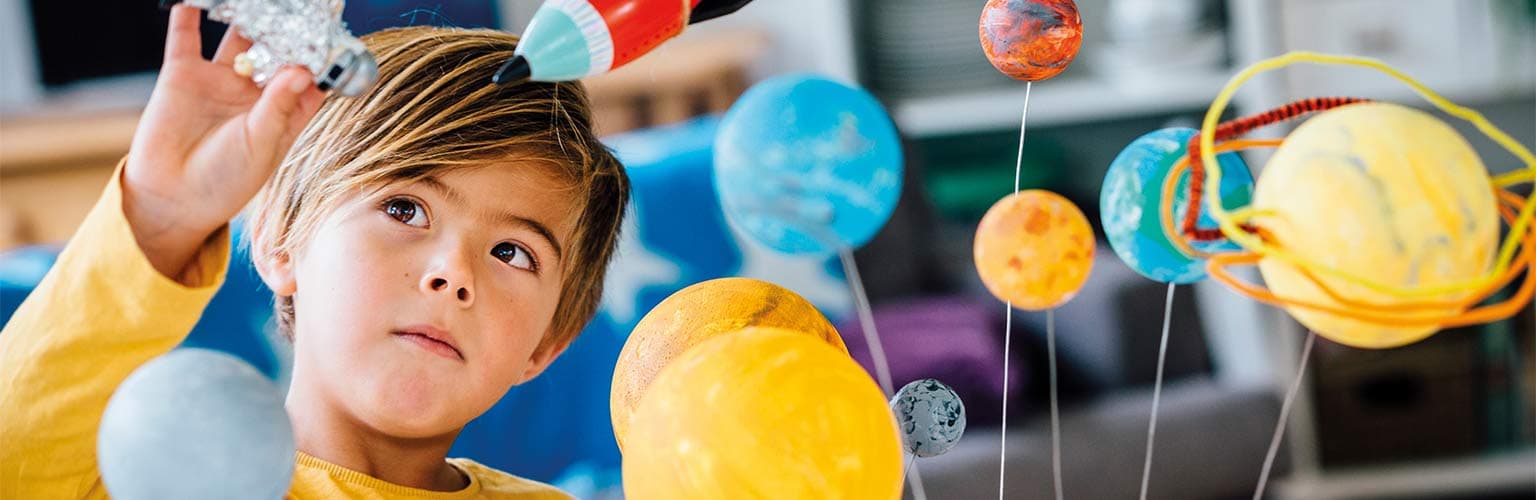 A child playing with a toy rocket and the toy solar system