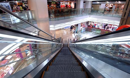 A view from the top of an escalator travelling downwards in a shopping mall