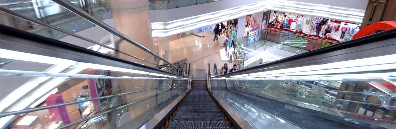 A view from the top of an escalator travelling downwards in a shopping mall