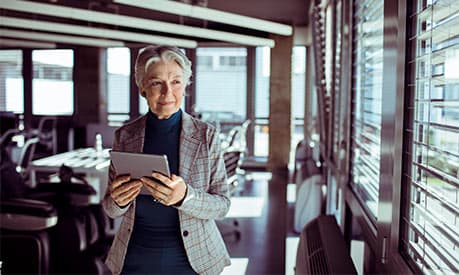 An elderly women in an office with a tablet