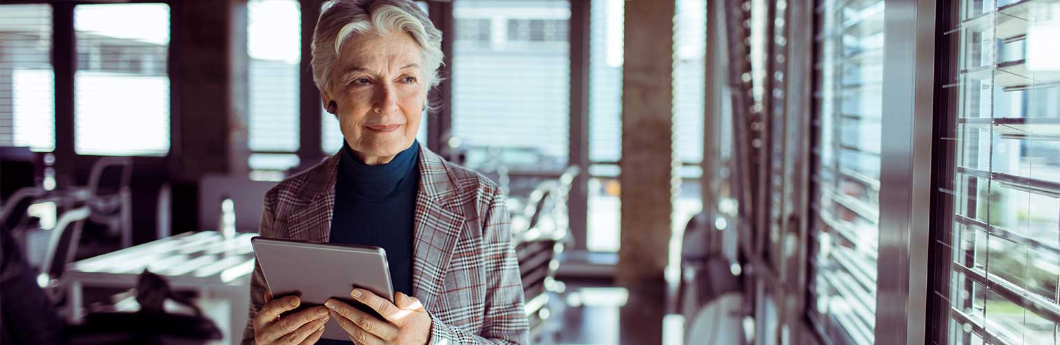 An elderly women in an office with a tablet