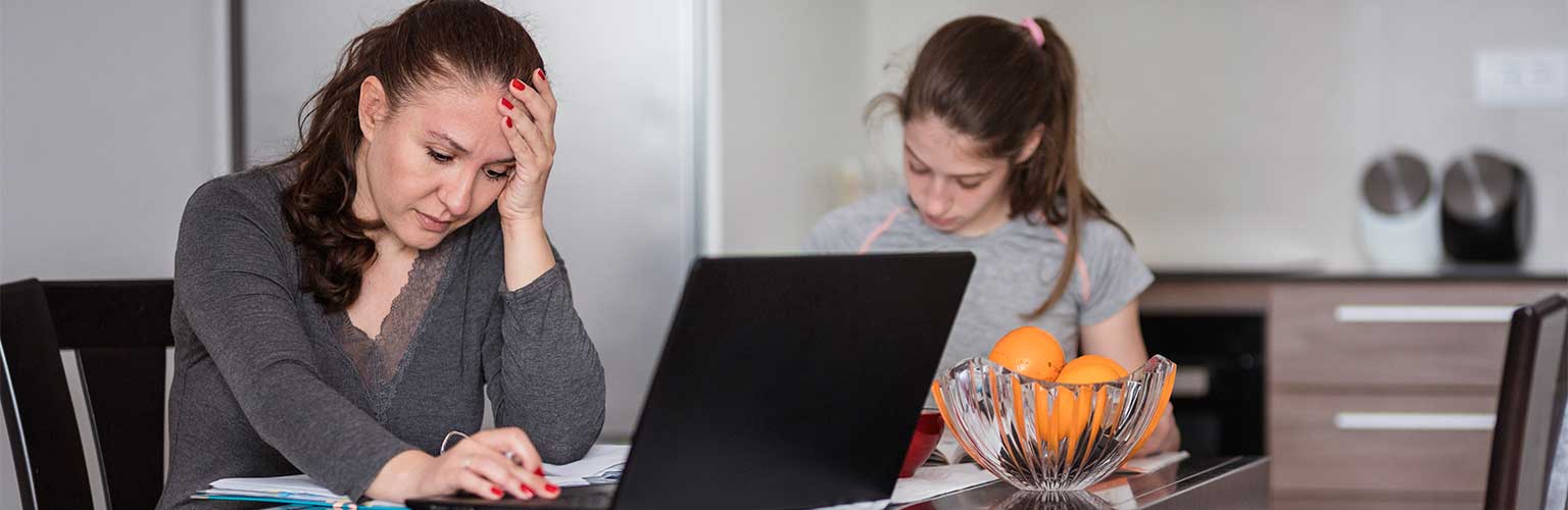 A woman looking stressed at home on her laptop 