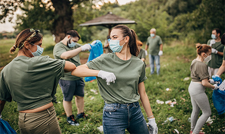 Group of volunteers with surgical masks cleaning nature together