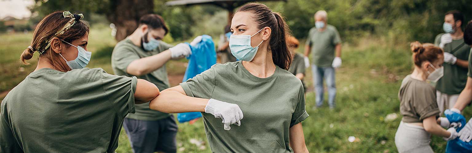 Group of volunteers with surgical masks cleaning nature together