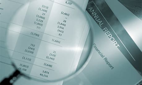 A magnifying glass looking at a paper financial report
