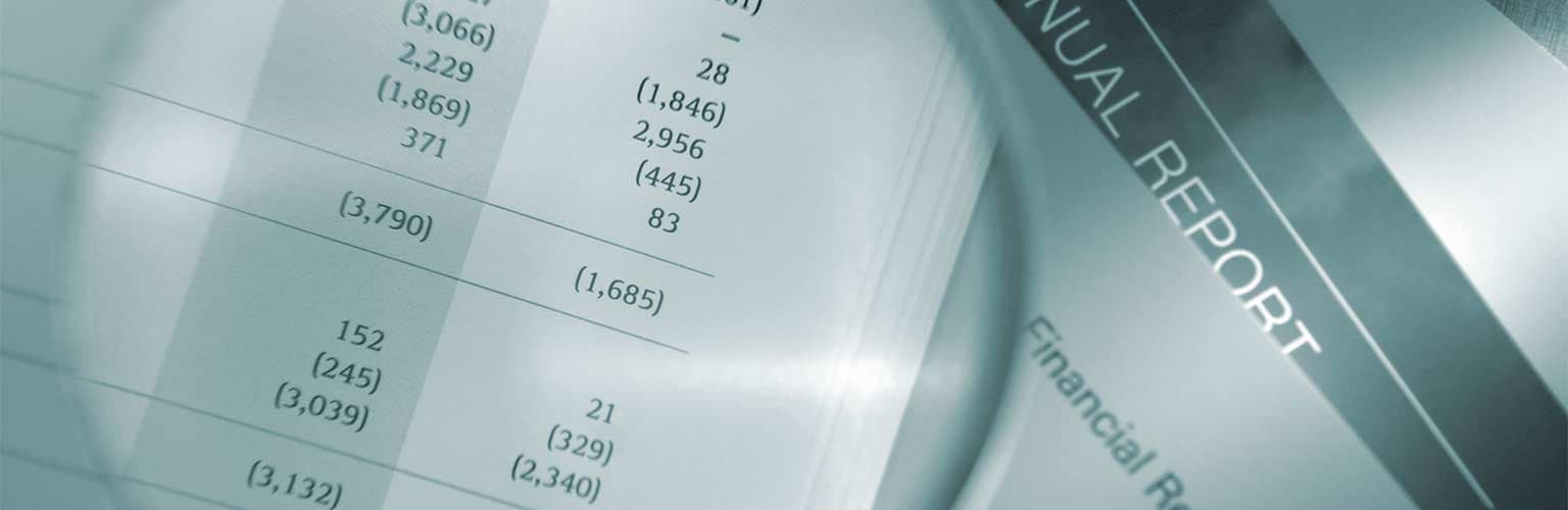 A magnifying glass looking at a paper financial report