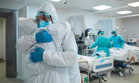 Two healthcare workers embracing in full ppe