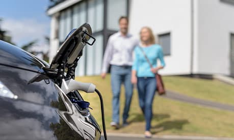 man and woman walking towards an electric car