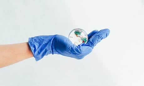 A crystal earth in the hand of someone wearing a medical glove