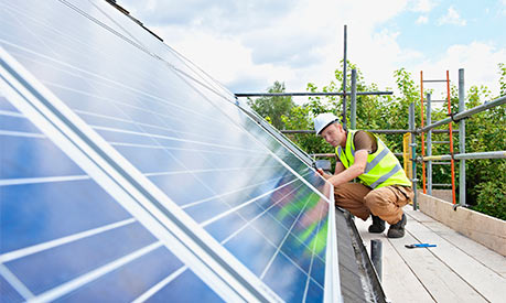 A construction worker installing solar panels on a roof