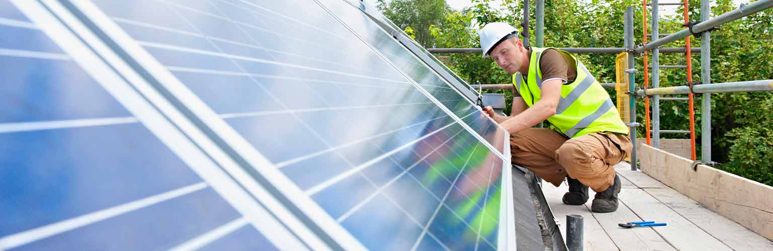 A construction worker installing solar panels on a roof