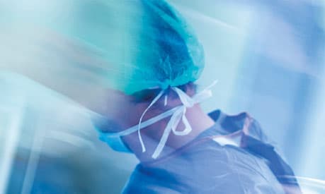 A healthcare worker in a surgical mask and scrubs