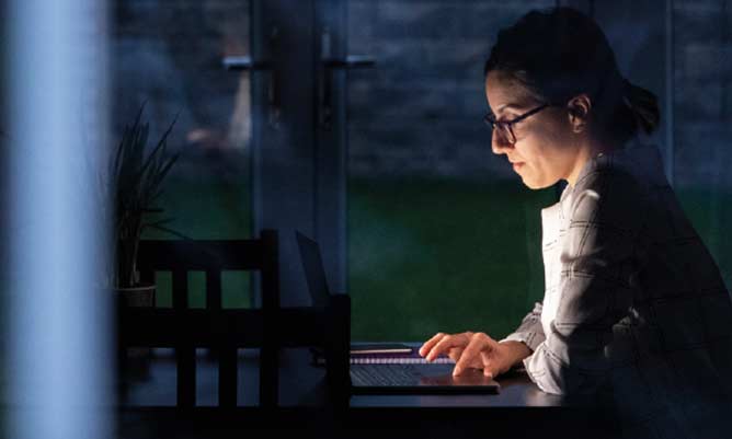 A woman working on her laptop in the dark
