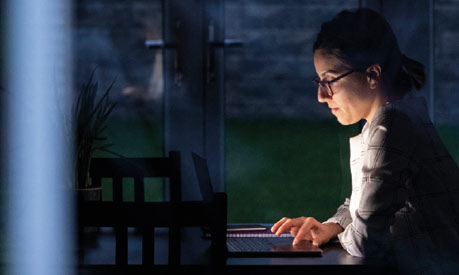 A woman working on her laptop in the dark