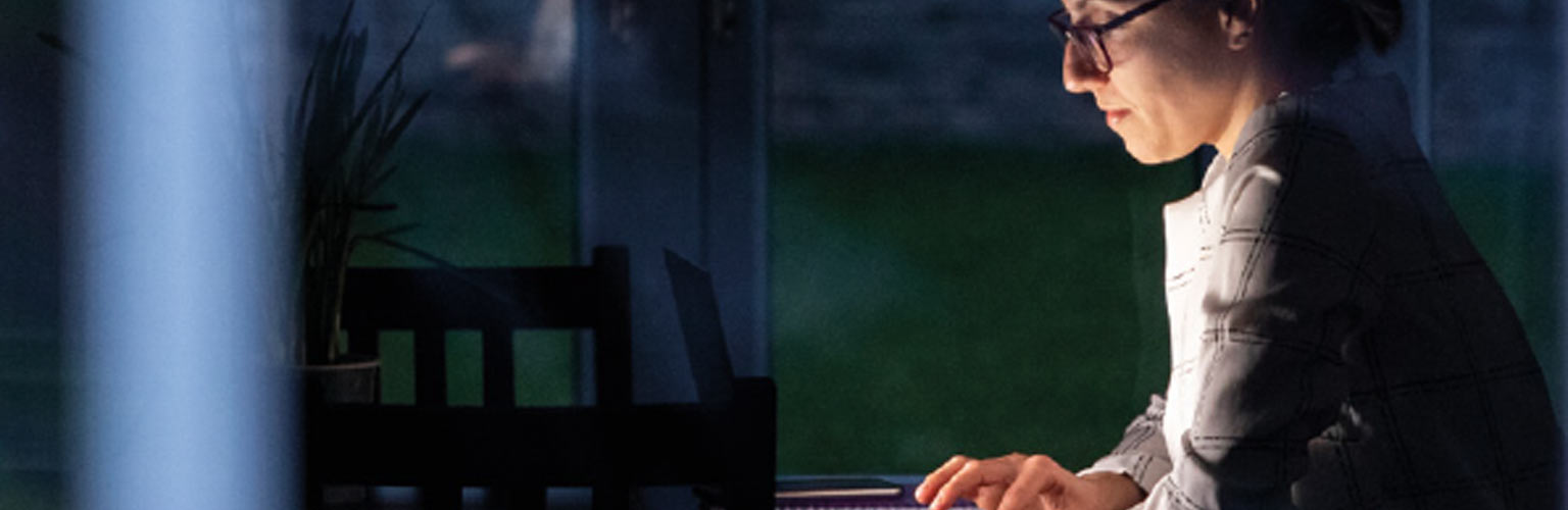 A woman working on her laptop in the dark