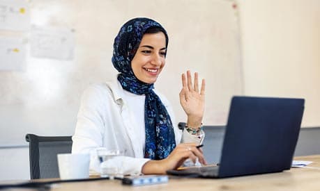 A woman raising her hand to a laptop screen