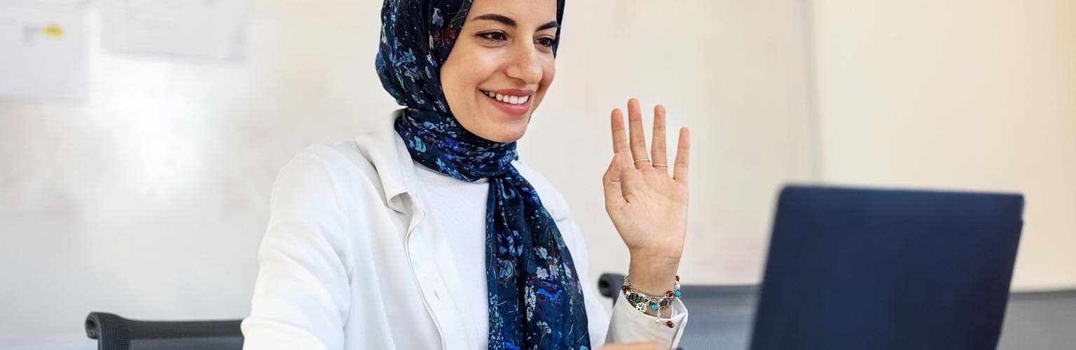 A woman raising her hand to a laptop screen