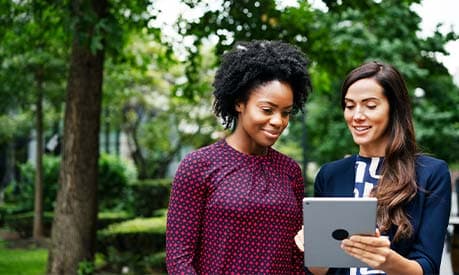 Two women looking at a smart device and smiling