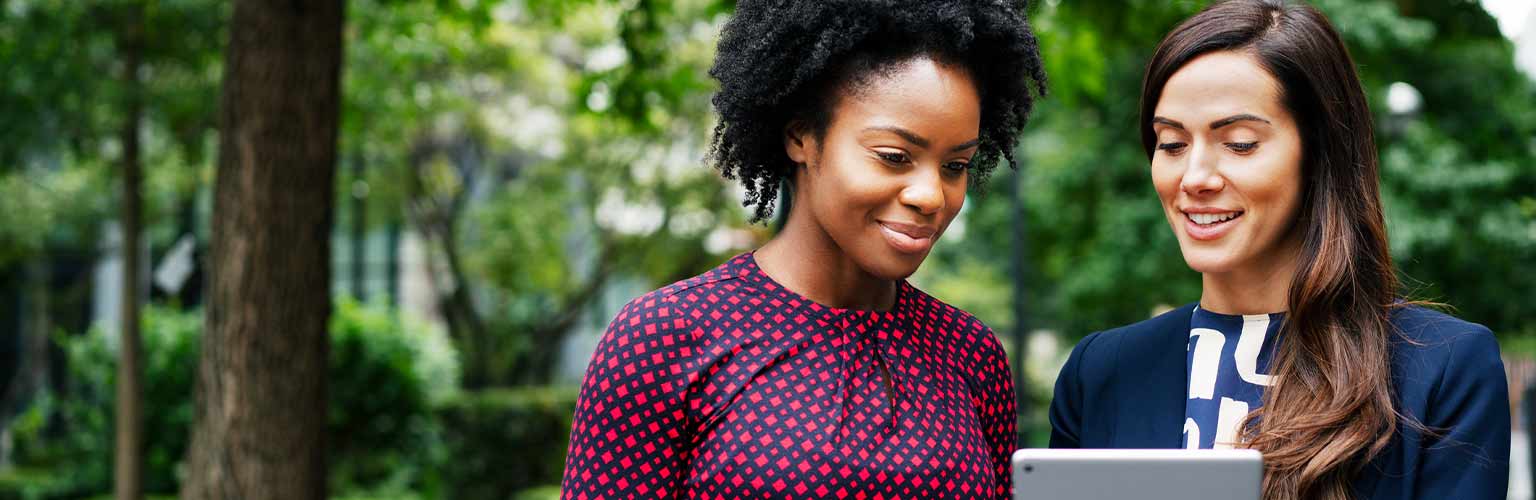 Two women looking at a smart device and smiling