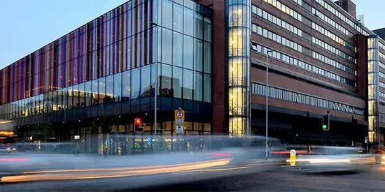 A building in Manchester at night, with cars driving past