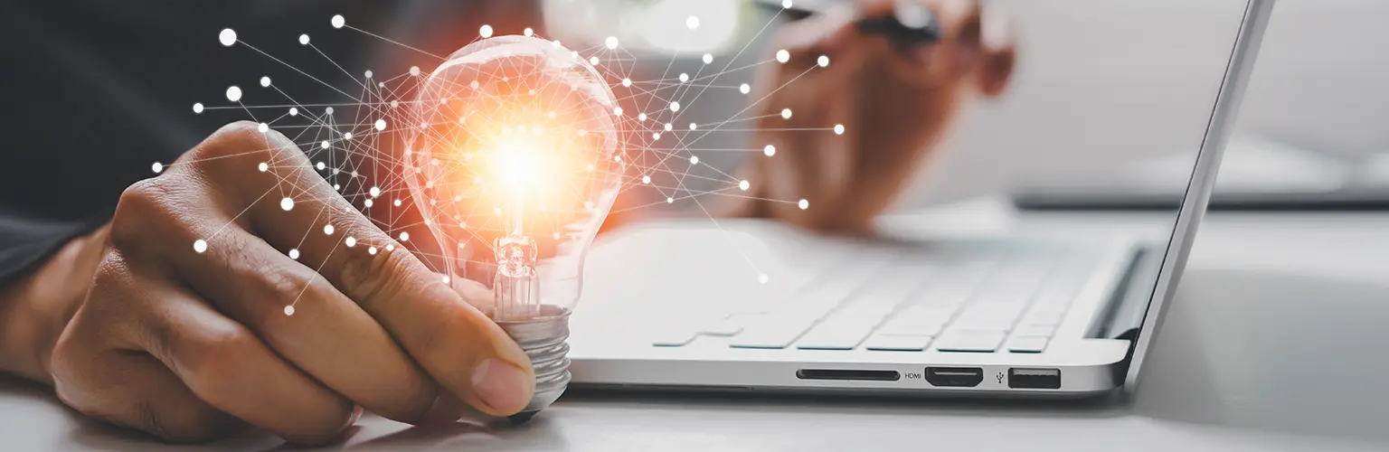 Male hand holding illuminated light bulb representing new ideas.