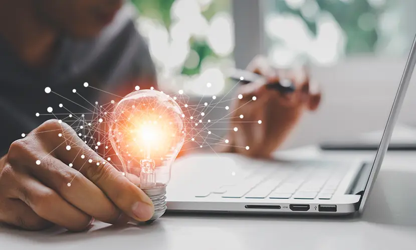 Male hand holding illuminated light bulb representing new ideas.