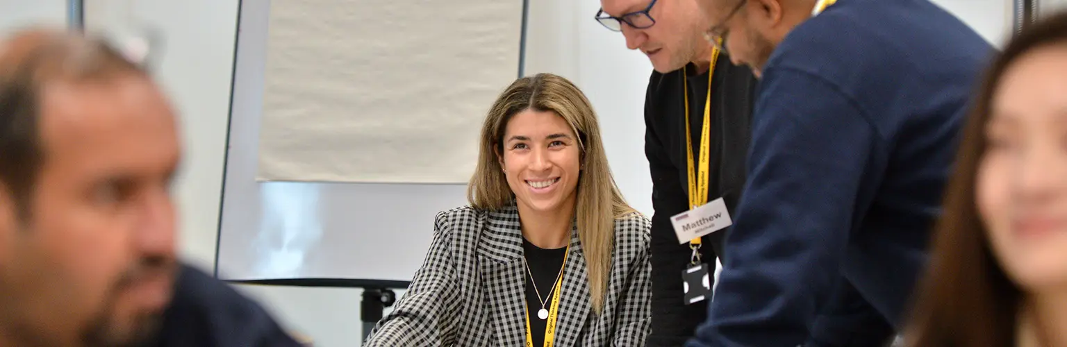 A female professional working on a group project sat on a table with two other male colleagues