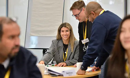 A female professional working on a group project sat on a table with two other male colleagues