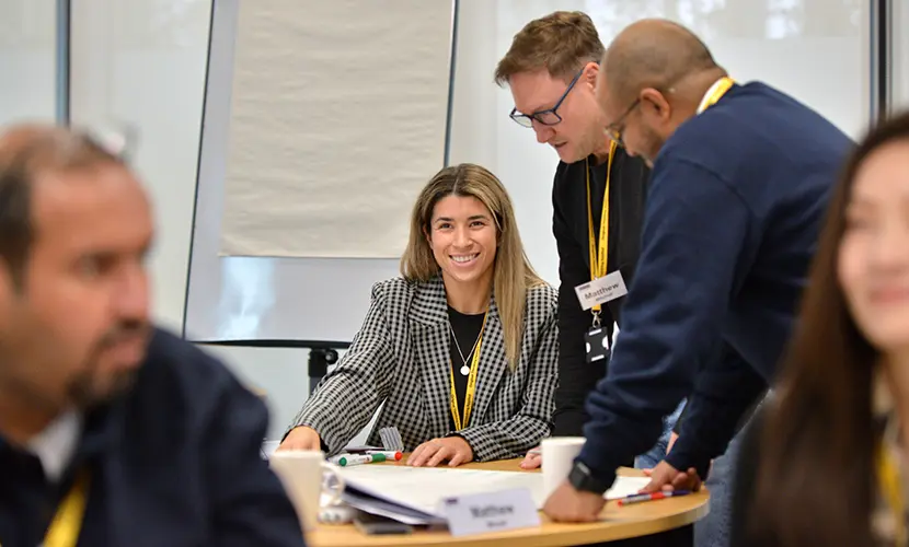 A female professional working on a group project sat on a table with two other male colleagues