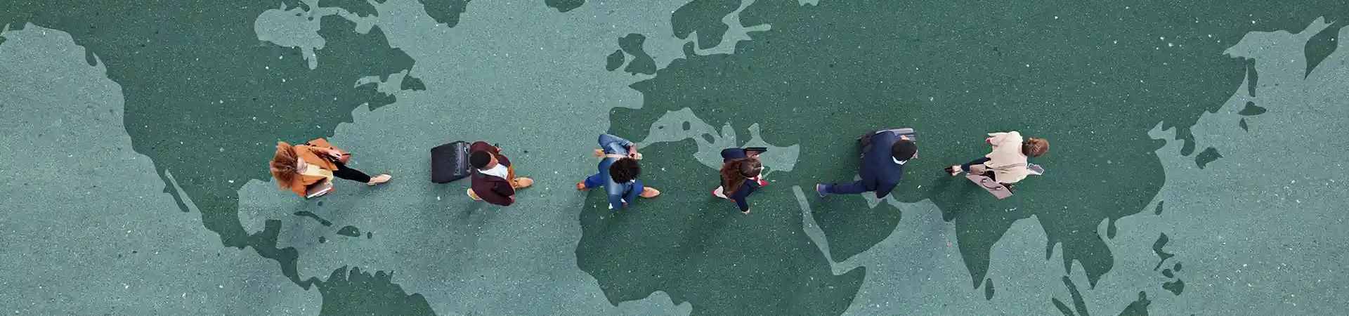 Group of young adults photographed from above walking on world map.