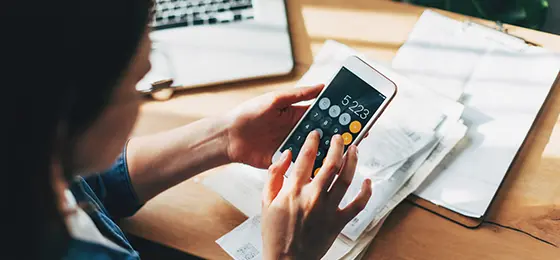 Close up Business woman using calculator and laptop for do math finance on wooden desk in office and business working background.